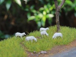 a close up of miniature figures of a herd of goats eating grass. Animal farm photo concept.