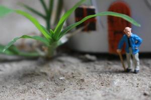 miniatura figura de un abuelo quien es esperando en frente de el casa. foto