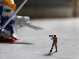 miniature figure of a photographer taking a photo of a robot.