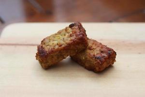 a close up of fried tempeh on a wooden cutting board photo