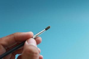 a close up of a hand holding a painting brush photo