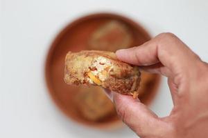 a close up of fried stuffed tofu or Gorengan Tahu Isi holding in hand photo