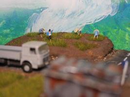 un miniatura diorama de un arroz campo y un la carretera como bien como varios personas y vehículos y edificios foto