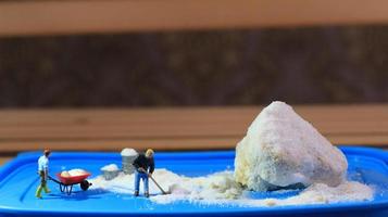 a miniature figure of a worker tidying a peanut cake sprinkled with powdered white sugar. concept of workers in the food industry. photo