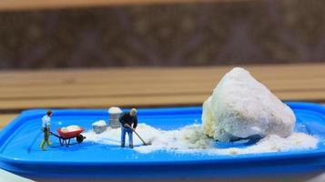 a miniature figure of a worker tidying a peanut cake sprinkled with powdered white sugar. concept of workers in the food industry. photo