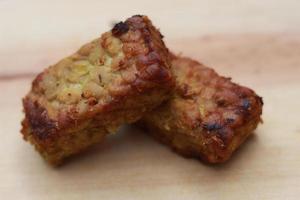 a close up of fried tempeh on a wooden cutting board photo
