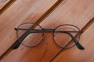 a close up of eyeglasses with black frames isolated natural patterned wooden background. photo