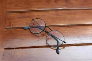 a close up of eyeglasses with black frames isolated natural patterned wooden background. photo