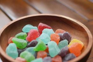 a close up of gummy candies of various colors and fruit flavors served in a wooden bowl. photo