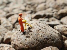 un cerca arriba de miniatura cifras de mineros aplastante roca. minería foto concepto.