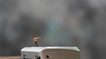 un miniatura figura tomando imagen con un cámara en contra un real cámara en el antecedentes. foto