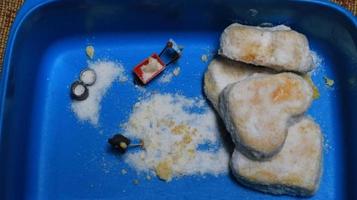 a miniature figure of a worker tidying a peanut cake sprinkled with powdered white sugar. concept of workers in the food industry. photo