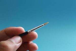 a close up of a hand holding a painting brush photo