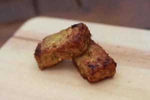 a close up of fried tempeh on a wooden cutting board photo