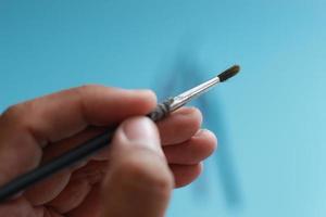 a close up of a hand holding a painting brush photo