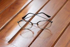 a close up of eyeglasses with black frames isolated natural patterned wooden background. photo