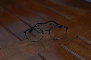 a close up of eyeglasses with black frames isolated natural patterned wooden background. photo