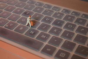 un miniatura figura de un oficina trabajador que lleva un maletín caminando Entre el teclados. foto