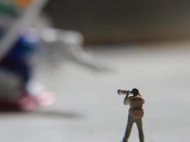 miniature figure of a photographer taking a photo of a robot.