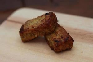 a close up of fried tempeh on a wooden cutting board photo