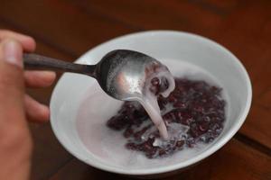 a bowl of black sticky rice porridge with coconut milk photo