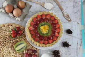 big fruit pie with toppings of strawberries, grapes, kiwi and pineapple. savory, sweet and fresh. Food concept photo. photo