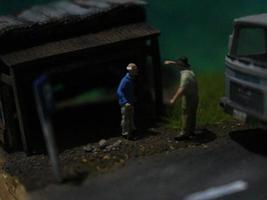 a close up of a miniature figure of an old man talking to other people in an old building by the side of the road. photo