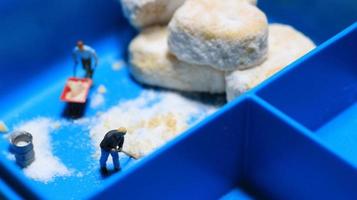 a miniature figure of a worker tidying a peanut cake sprinkled with powdered white sugar. concept of workers in the food industry. photo