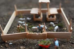 A close up of miniature figure of a goat herder feeding in a wooden cage. Shepherd concept. photo