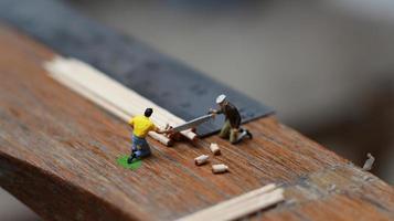 Miniature figure of a worker cutting toothpicks. carpenter activity photo concept.