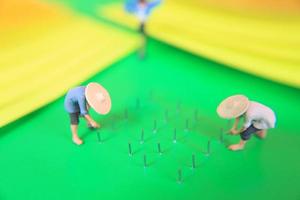 miniature figure of farmers growing crops in the form of staples on green paper. Concept of agriculture photo. photo