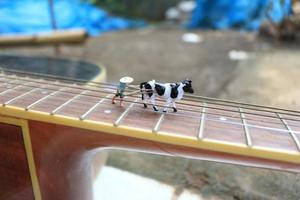 miniature figure of a farmer plowing a field with his cow on a guitar. photo