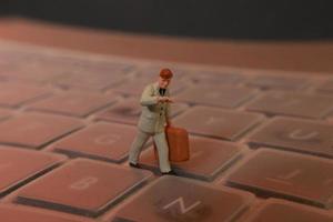 a miniature figure of an office worker carrying a briefcase walking between the keyboards. photo