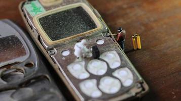 miniature figure of a technician repairing an old broken cell phone. working technician concept. photo