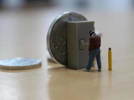 miniature figure of a robber who is trying to break into a safe of money. photo