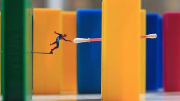 a miniature human figure with the power of a spider jumping over a colored block toy. their concept of reimagining superheroes. photo