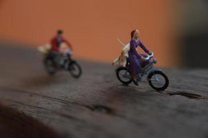 Bogor, Indonesia - December, 12 2022. miniature figures of two cyclists crossing a wooden road. photo