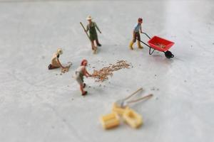 miniatura cifras de trabajadores trabajando juntos a moverse grano. foto