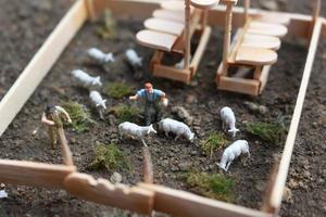 A close up of miniature figure of a goat herder feeding in a wooden cage. Shepherd concept. photo