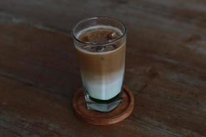 a glass of pandan coffee latte served cold on the table. photo