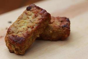 a close up of fried tempeh on a wooden cutting board. photo
