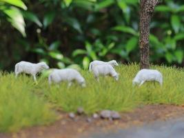 a close up of miniature figures of a herd of goats eating grass. Animal farm photo concept.