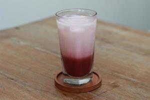 a glass of red velvet latte served cold on the table. photo