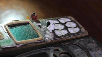 miniature figure of a technician repairing an old broken cell phone. working technician concept. photo