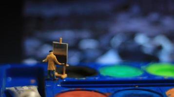 a miniature figure of a painter painting a landscape on watercolors. artist concept. photo