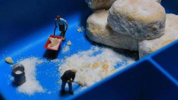 a miniature figure of a worker tidying a peanut cake sprinkled with powdered white sugar. concept of workers in the food industry. photo