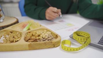 il giovane donna è ottenere se stessa un' dieta programma. il donna è preparazione un' dieta elenco di guardare a il Internet a casa. video