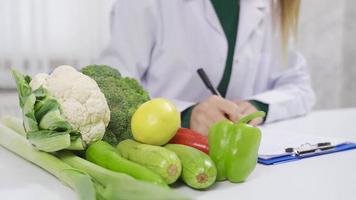 comendo saudável. dietista é preparando uma vegetal dieta. a dietista prepara uma dieta Lista para dele pacientes com saudável legumes. video