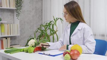 nutritionniste qui prépare repas des plans. le diététicien prépare une régime liste pour le sien les patients avec en bonne santé des légumes. video