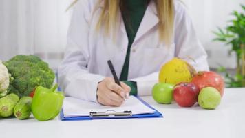 The dietitian writes a diet list of healthy vegetables and fruits. Vegetable diet. Nutritionist offers healthy vegetable and fruit diet. video